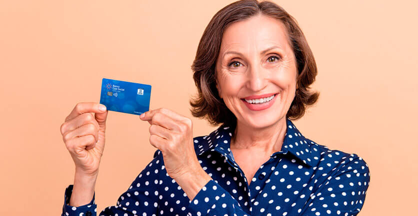 Mujer pensionada sonriendo con una tarjeta en sus manos