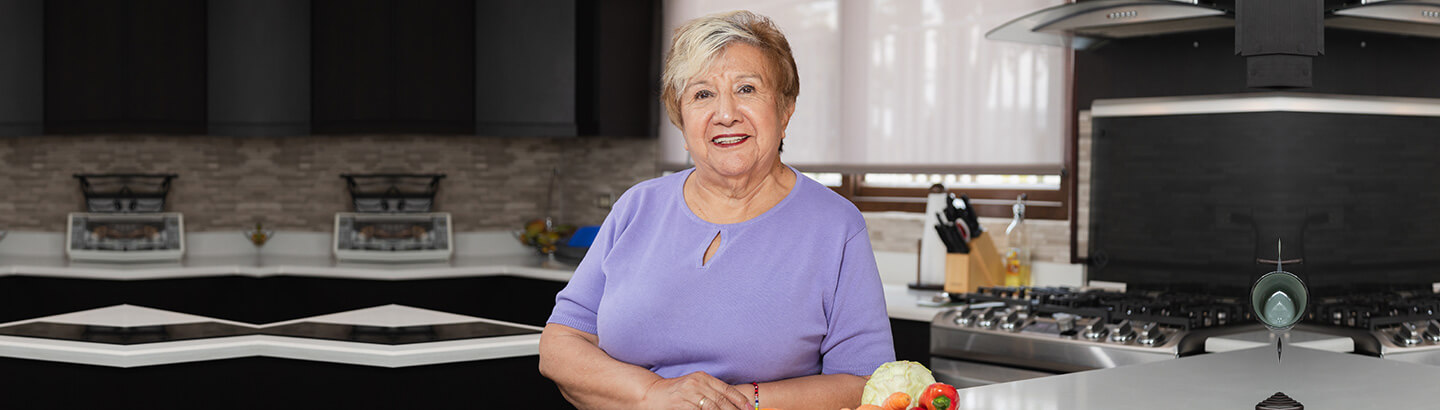 Mesada pensional mujer jubilada feliz en su cocina