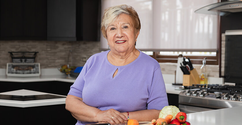 Mesada pensional mujer jubilada feliz en su cocina