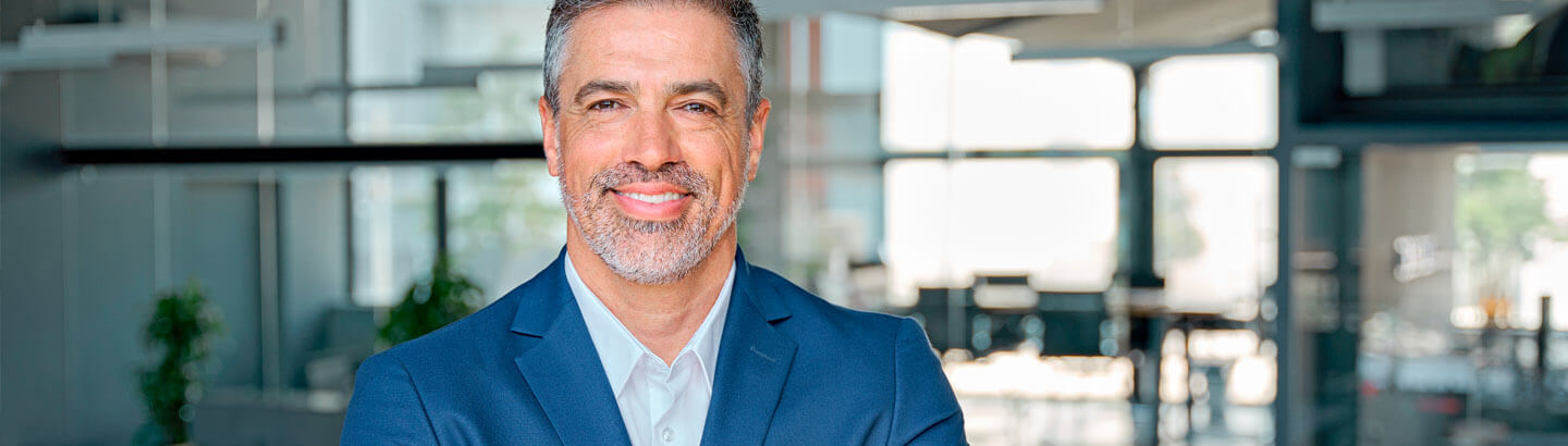 Hombre empresario en su oficina sonriendo con sus brazos cruzados