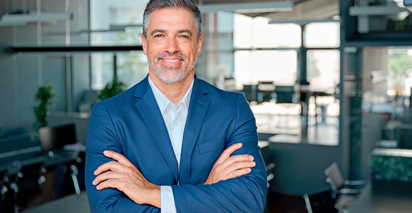 Hombre empresario en su oficina sonriendo con sus brazos cruzados