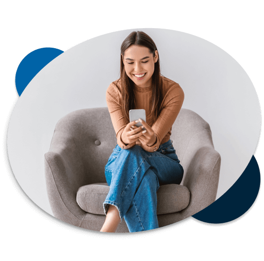 Joven sentada en un mueble sonriendo con un celular en la mano